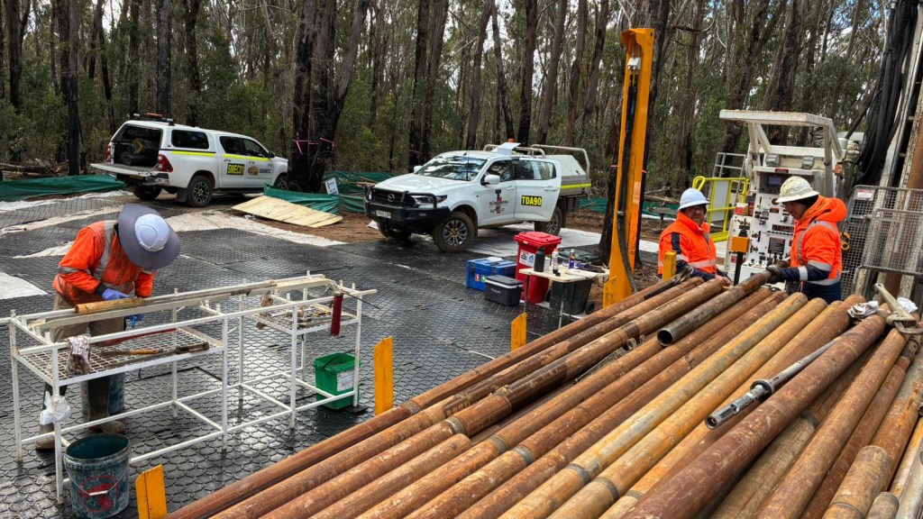 orkers conducting drilling operations with equipment and trucks in a forested site.