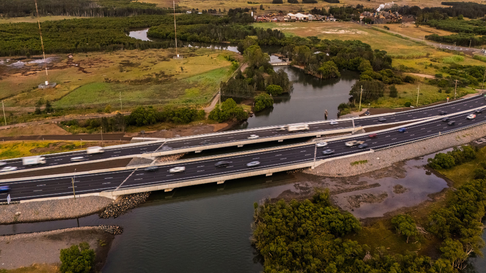 Aerial view of a multi-lane highway bridge crossing a winding river and wetlands in Hexham.