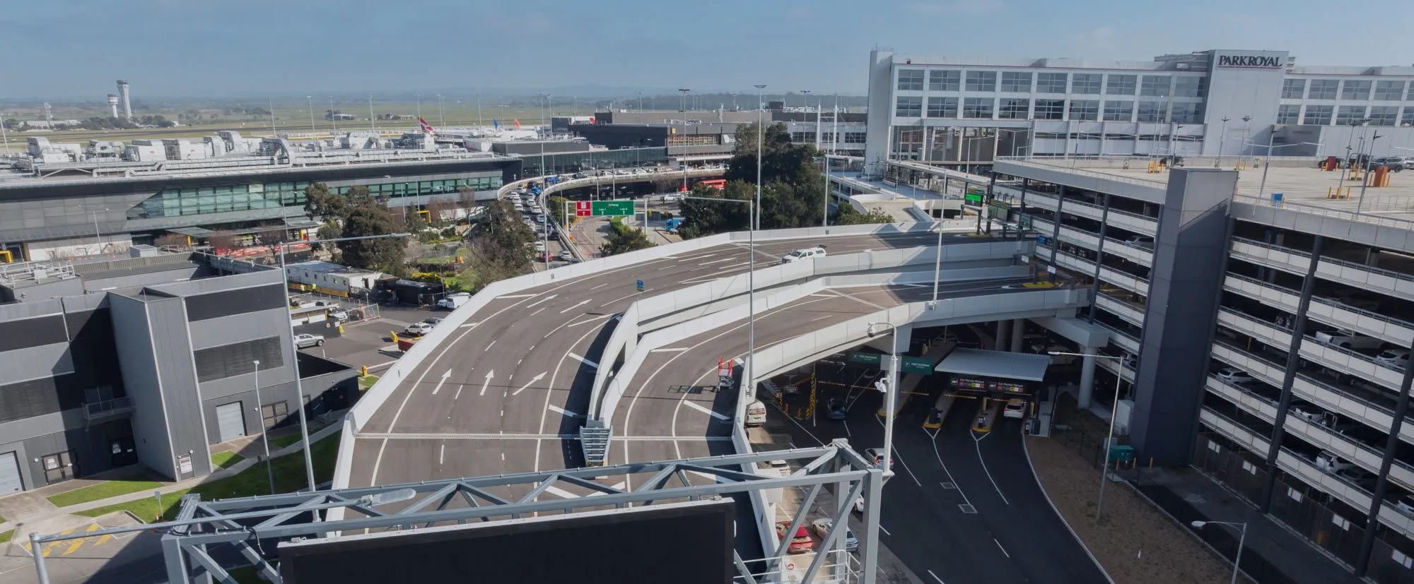 Aerial view of Melbourne Airport’s Naarm Way with elevated roadways, terminal buildings, and parking facilities.