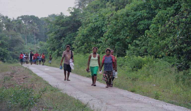 Community members travelling on a rural road in Vanuatu.